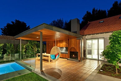 Halbschattiger Moderner Garten hinter dem Haus mit Feuerstelle und Dielen in Melbourne