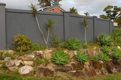 Imagen de jardín moderno de tamaño medio en verano en patio delantero con exposición total al sol y adoquines de piedra natural