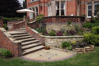 Modelo de jardín clásico grande en patio trasero con adoquines de piedra natural