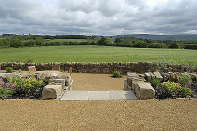 Exemple d'un grand jardin arrière éclectique avec un mur de soutènement, une exposition ensoleillée et des pavés en pierre naturelle.
