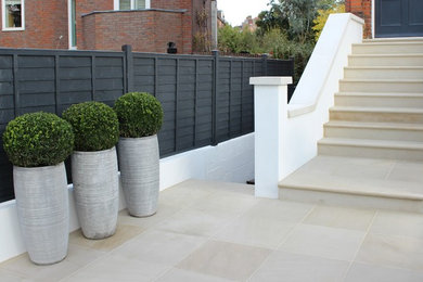 Photo of a mid-sized contemporary full sun front yard stone landscaping in London.
