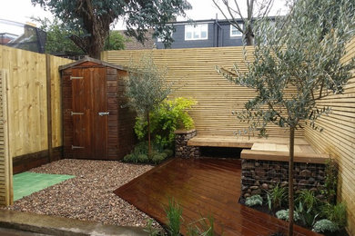 Small contemporary back formal partial sun garden in London with decking.