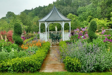 Imagen de jardín tradicional de tamaño medio en verano en patio trasero con jardín francés, exposición total al sol y adoquines de piedra natural