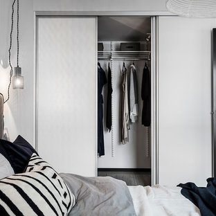 Foto de armario unisex, nórdico, de tamaño medio, con armarios con paneles lisos, puertas de armario blancas, suelo de madera clara y suelo gris