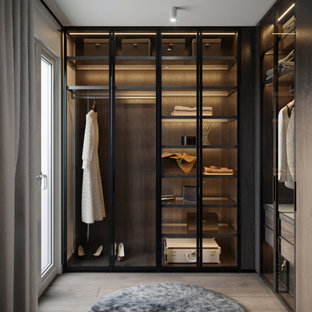 Foto di una cabina armadio unisex design di medie dimensioni con ante di vetro, ante nere, pavimento in legno massello medio e pavimento beige