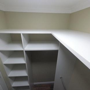 Modelo de armario vestidor unisex, tradicional renovado, de tamaño medio, con armarios con puertas mallorquinas, puertas de armario blancas, suelo laminado y suelo marrón