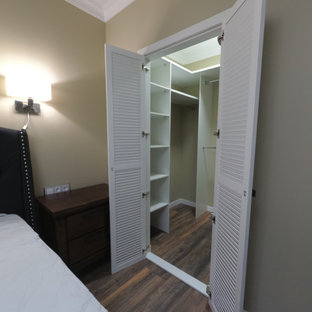 Modelo de armario vestidor unisex, clásico renovado, de tamaño medio, con armarios con puertas mallorquinas, puertas de armario blancas, suelo laminado y suelo marrón