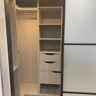 Foto di una piccola cabina armadio per uomo industriale con pavimento in laminato e pavimento beige