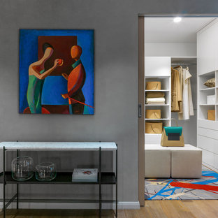 Foto di una piccola cabina armadio unisex contemporanea con ante bianche, moquette, pavimento multicolore e ante lisce