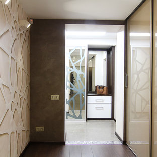 Modelo de armario vestidor actual, de tamaño medio, con armarios tipo vitrina, puertas de armario beige y suelo de madera oscura