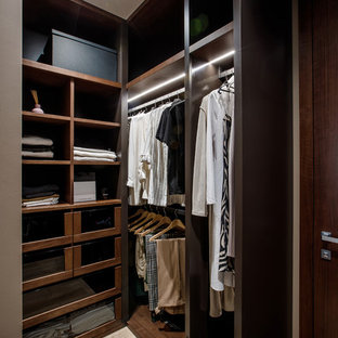 Esempio di una piccola cabina armadio unisex minimal con ante di vetro, ante in legno bruno e pavimento in legno massello medio