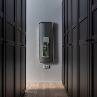 Modelo de armario vestidor unisex, nórdico, de tamaño medio, con armarios con paneles con relieve, puertas de armario negras, suelo laminado y suelo marrón