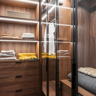 Immagine di una piccola cabina armadio unisex contemporanea con ante di vetro, ante in legno scuro, moquette e pavimento multicolore