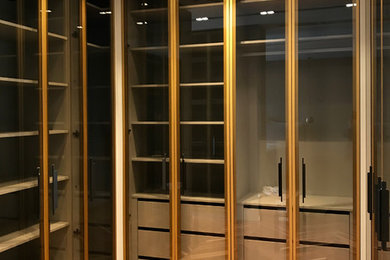 На фото: большая гардеробная комната в современном стиле с стеклянными фасадами с
