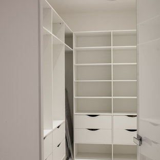 Ejemplo de armario vestidor unisex, actual, de tamaño medio, con armarios abiertos, puertas de armario blancas, suelo laminado y suelo beige