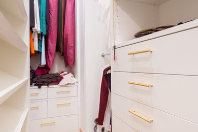 Diseño de armario vestidor contemporáneo de tamaño medio con armarios con paneles lisos, puertas de armario blancas, suelo de madera en tonos medios y suelo blanco