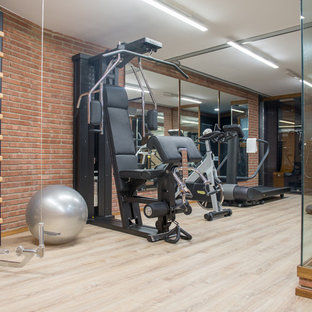 Multifunktionaler, Mittelgroßer Industrial Fitnessraum mit oranger Wandfarbe und hellem Holzboden in Barcelona