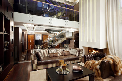 Пример оригинального дизайна: парадная гостиная комната в современном стиле с темным паркетным полом, стандартным камином и коричневым диваном