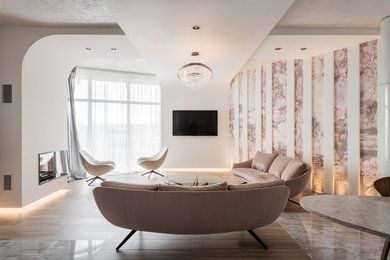 Стильный дизайн: большая открытая, объединенная гостиная комната в современном стиле с белыми стенами, двусторонним камином, фасадом камина из штукатурки, телевизором на стене и коричневым полом - последний тренд