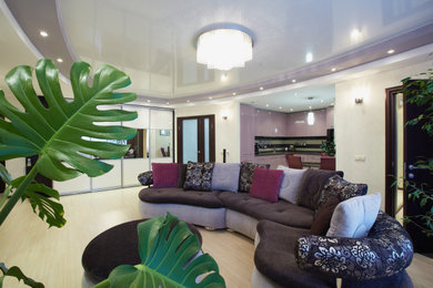 Foto de salón con barra de bar abierto contemporáneo de tamaño medio con paredes beige, suelo laminado, pared multimedia y suelo beige