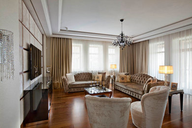 Imagen de salón contemporáneo con paredes beige, suelo de madera en tonos medios y televisor colgado en la pared