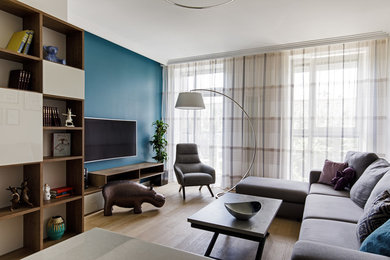 Стильный дизайн: открытая гостиная комната среднего размера в современном стиле с с книжными шкафами и полками, бежевыми стенами, светлым паркетным полом, телевизором на стене и бежевым полом - последний тренд