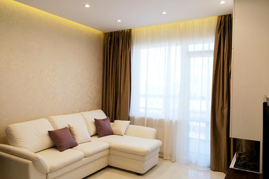 На фото: изолированная гостиная комната среднего размера в современном стиле с бежевыми стенами, полом из керамической плитки, телевизором на стене, бежевым полом и тюлем на окнах