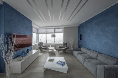 Diseño de salón para visitas abierto contemporáneo de tamaño medio sin chimenea con paredes azules, suelo de madera clara, televisor colgado en la pared y suelo beige