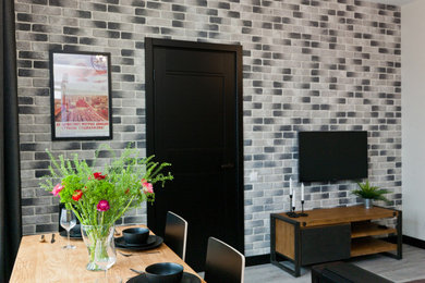 Foto de salón cerrado industrial de tamaño medio con paredes blancas, suelo laminado, televisor colgado en la pared, suelo gris y ladrillo