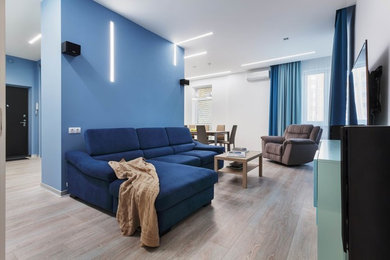 Источник вдохновения для домашнего уюта: открытая гостиная комната среднего размера в современном стиле с синими стенами, полом из ламината, телевизором на стене и коричневым полом