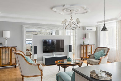 На фото: большая открытая гостиная комната в стиле неоклассика (современная классика) с серыми стенами, светлым паркетным полом и телевизором на стене
