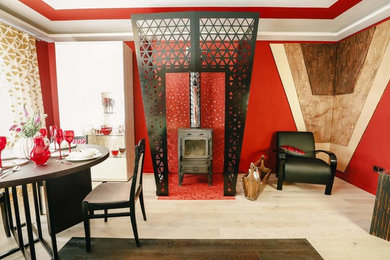 Источник вдохновения для домашнего уюта: изолированная гостиная комната среднего размера в стиле фьюжн с красными стенами, светлым паркетным полом, стандартным камином и фасадом камина из металла без телевизора