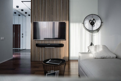 Стильный дизайн: гостиная комната среднего размера в современном стиле с белыми стенами, темным паркетным полом, телевизором на стене и коричневым полом - последний тренд