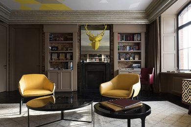 Immagine di un soggiorno chic chiuso con libreria, pareti beige, camino classico e pavimento nero
