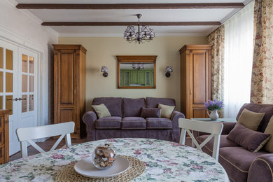 На фото: маленькая изолированная, объединенная гостиная комната в стиле кантри с бежевыми стенами, полом из ламината, телевизором на стене и коричневым полом для на участке и в саду с