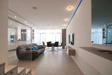 Источник вдохновения для домашнего уюта: двухуровневая гостиная комната среднего размера в современном стиле с белыми стенами, полом из керамогранита и телевизором на стене