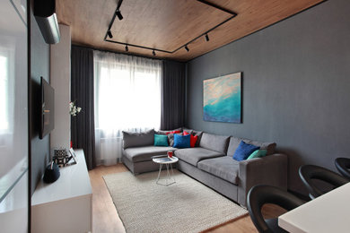 На фото: открытая гостиная комната среднего размера в стиле фьюжн с домашним баром, серыми стенами, полом из ламината, телевизором на стене и коричневым полом с
