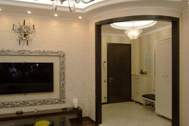 Modelo de salón cerrado clásico renovado de tamaño medio con paredes beige, suelo de madera oscura, televisor colgado en la pared y suelo marrón
