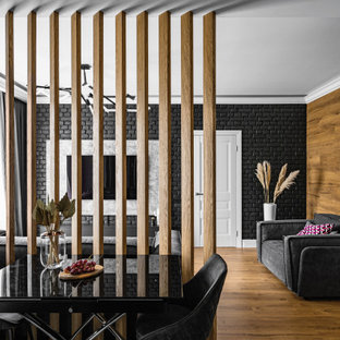 Esempio di un soggiorno minimal di medie dimensioni con pareti nere, pavimento in legno massello medio, TV a parete, soffitto ribassato e pareti in mattoni