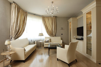 Immagine di un soggiorno classico di medie dimensioni e chiuso con libreria, pareti beige, parquet chiaro, TV a parete e pavimento beige