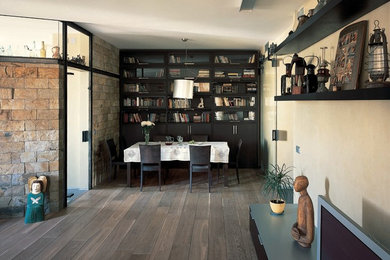 Modelo de biblioteca en casa cerrada de tamaño medio sin chimenea con paredes beige, suelo de madera en tonos medios, pared multimedia y suelo marrón