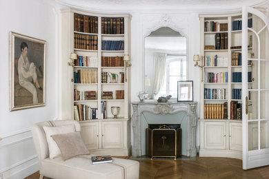 Inspiration pour un salon traditionnel avec une bibliothèque ou un coin lecture, un mur blanc, un sol en bois brun, une cheminée standard, un sol beige et un manteau de cheminée en pierre.
