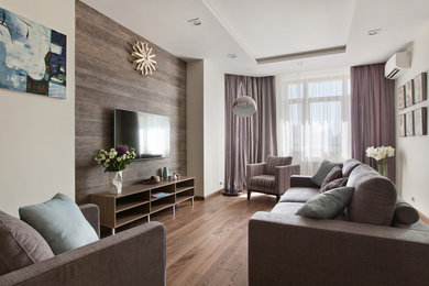Immagine di un soggiorno design con pareti bianche, pavimento in legno massello medio, TV a parete e pavimento marrone