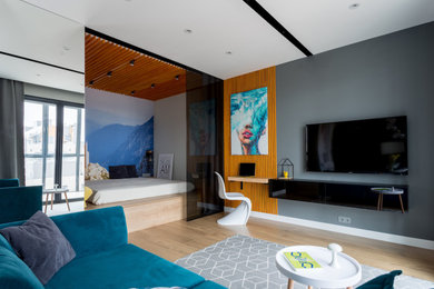 Пример оригинального дизайна: маленькая гостиная комната в современном стиле с серыми стенами, паркетным полом среднего тона, телевизором на стене и коричневым полом для на участке и в саду