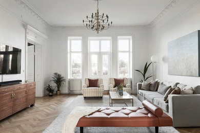 Пример оригинального дизайна: гостиная комната в стиле неоклассика (современная классика) с белыми стенами, светлым паркетным полом, телевизором на стене и коричневым полом