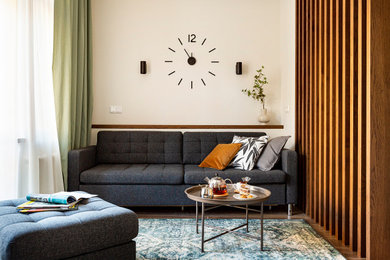 Пример оригинального дизайна: маленькая открытая гостиная комната в современном стиле с с книжными шкафами и полками, бежевыми стенами, полом из ламината и коричневым полом для на участке и в саду