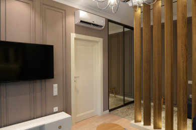 Ejemplo de salón abierto tradicional renovado pequeño con paredes marrones, suelo de madera clara, televisor colgado en la pared y suelo marrón
