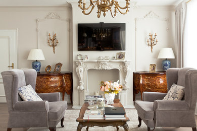 Ejemplo de salón para visitas abierto clásico con paredes blancas, televisor colgado en la pared, suelo beige y suelo de madera en tonos medios