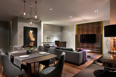 Стильный дизайн: парадная, открытая гостиная комната среднего размера в современном стиле с серыми стенами, паркетным полом среднего тона, телевизором на стене и коричневым полом без камина - последний тренд