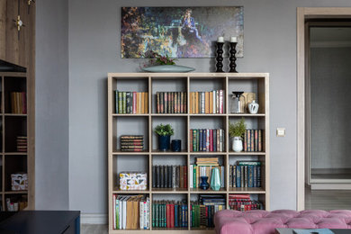 Imagen de biblioteca en casa cerrada contemporánea de tamaño medio con paredes grises, suelo laminado, televisor independiente y suelo beige